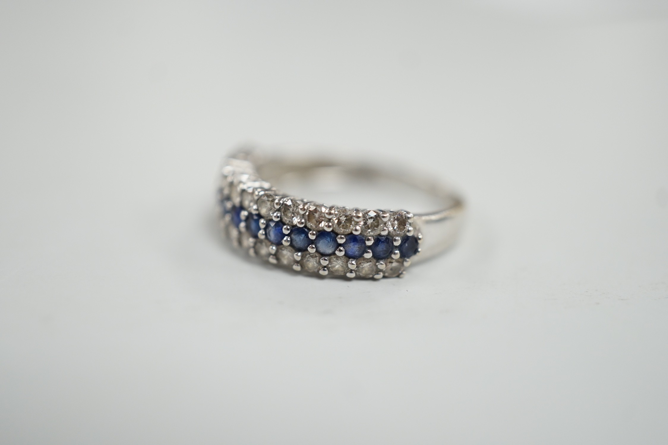 A modern 750 white metal, sapphire and diamond set three row half hoop ring, size M, gross weight 2.5 grams.
